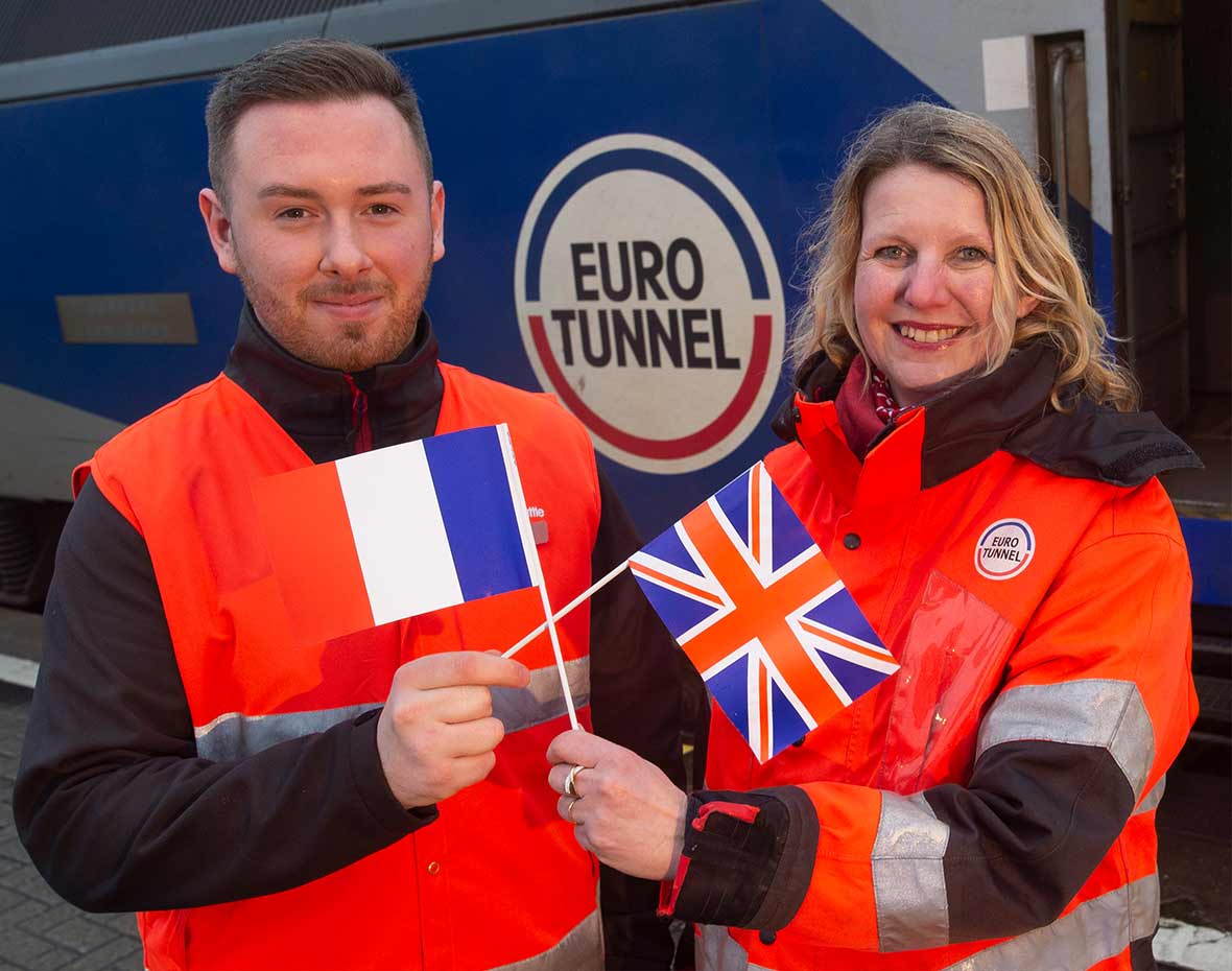 Les équipes françaises et anglaises d’Eurotunnel posent avec un drapeau devant la navette